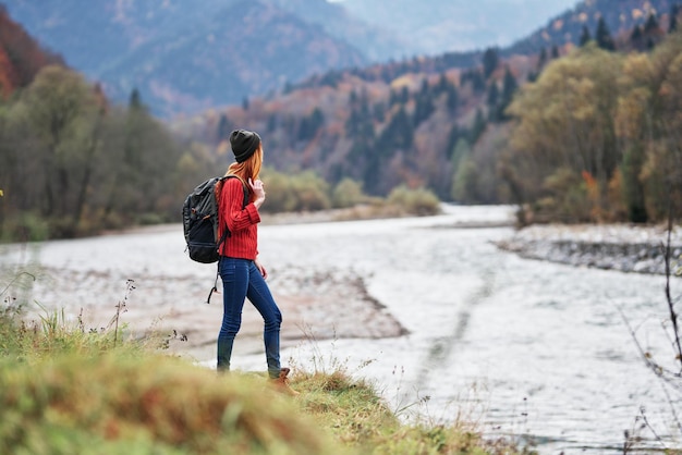 Jeune femme avec sac à dos dans les montagnes automne voyage tourisme paysage rivière eau peu profonde