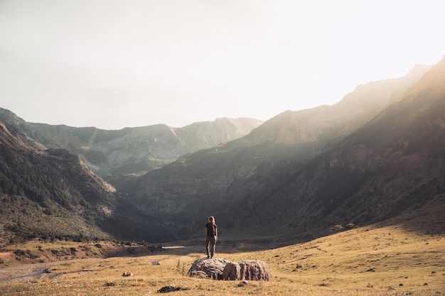 Une jeune femme avec un sac à dos sur le sommet d'un rocher dans un beau paysage sauvage Concept de destination de voyage de découverte