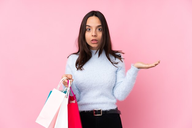 Jeune femme avec sac à provisions sur rose isolé faisant le geste de doutes