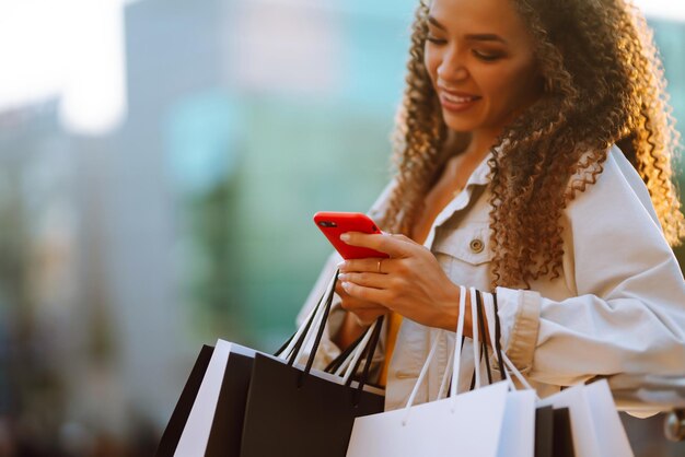 Une jeune femme avec des sacs d'achat marchant dans la rue Concept de vente