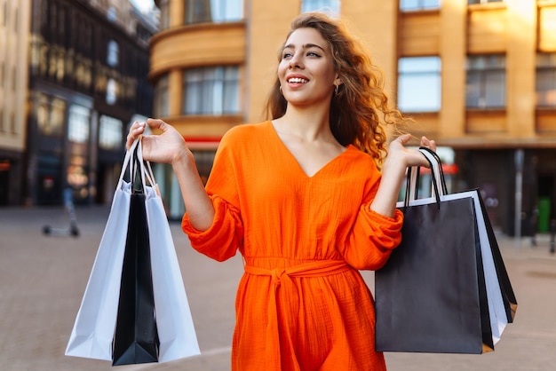 Jeune femme avec des sacs à provisions dans la ville Concept de vente ou d'achat de vacances