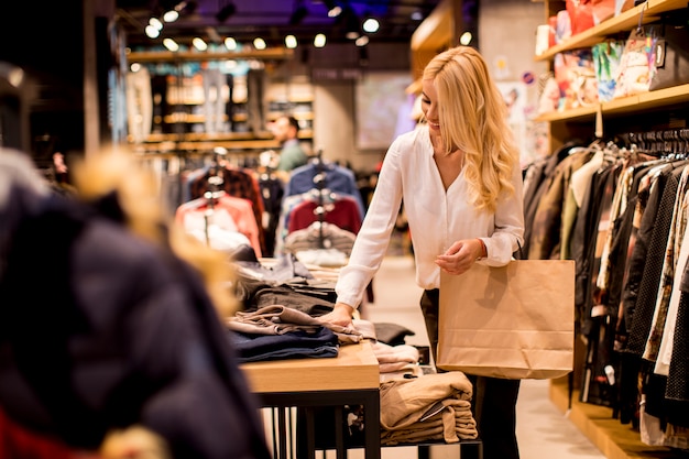 Jeune femme avec des sacs à provisions debout dans le magasin de vêtements