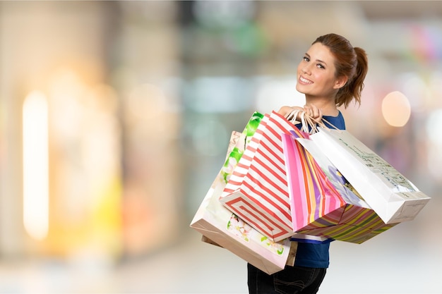 Jeune femme avec des sacs à provisions sur fond flou de centre commercial