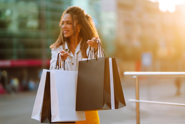 Jeune femme avec des sacs à provisions marchant dans la rue Concept de vente