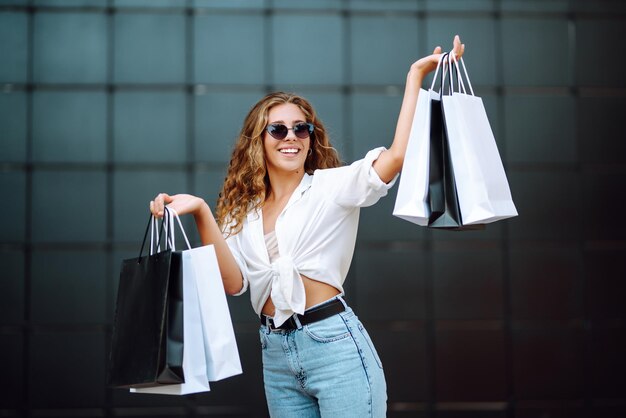 Jeune femme avec des sacs à provisions marchant dans la rue Shopping d'été Concept de mode de vie de vente shopping