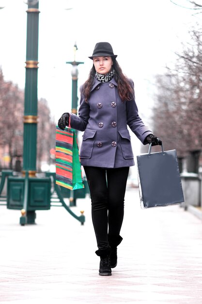 Jeune femme avec des sacs à provisions marchant dans la rue de la ville.