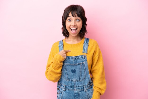 Jeune femme avec une salopette fond isolé avec une expression faciale surprise