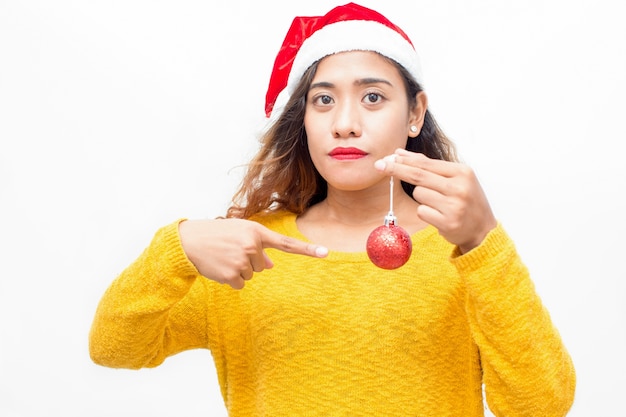 Jeune femme sans sourire, pointant sur la boule de Noël