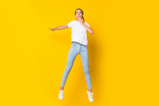 Jeune femme sautant isolé sur un mur jaune