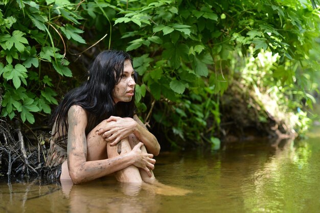 Jeune femme sauvage en vêtements noirs posant dans la rivière