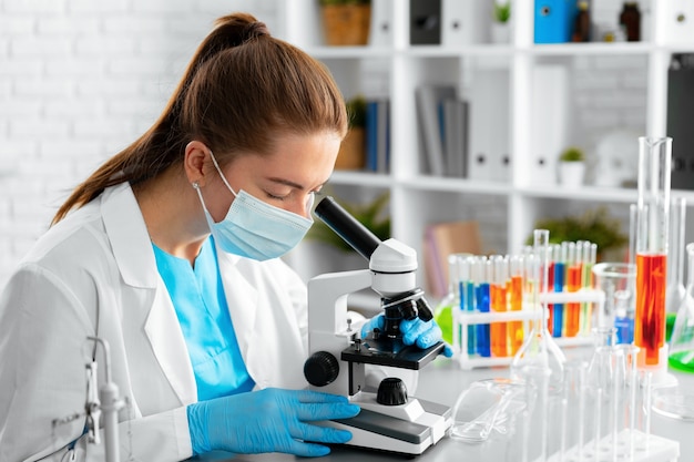 Jeune femme scientifique à l'aide d'un microscope en laboratoire close up