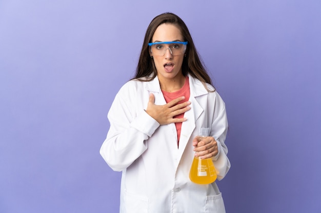 Jeune femme scientifique sur fond isolé surpris et choqué en regardant à droite