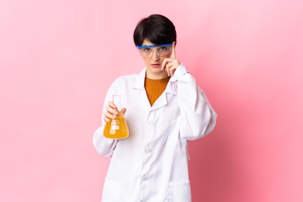 Jeune femme scientifique isolée sur mur rose pensant une idée