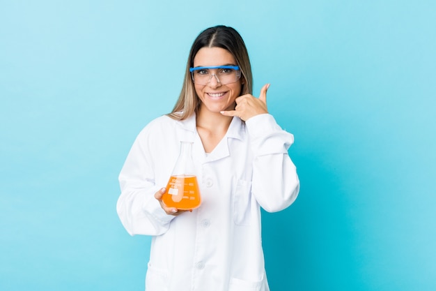 Jeune femme scientifique montrant un geste d'appel de téléphone mobile avec les doigts.