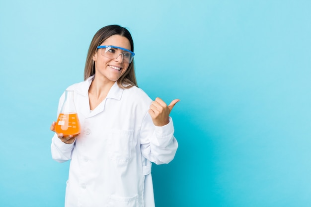 Jeune femme scientifique pointe le doigt du pouce, riant et insouciant.