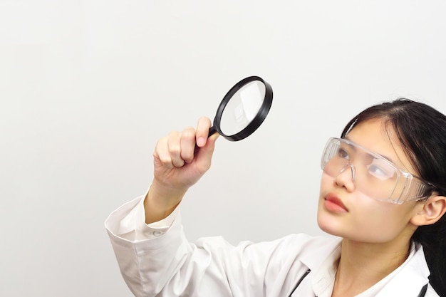 Jeune femme scientifique regardant quelque chose à travers une loupe