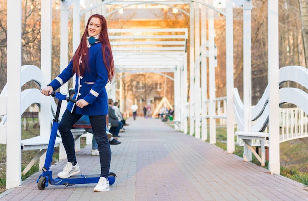 Jeune femme sur un scooter électrique bleu dans le parc