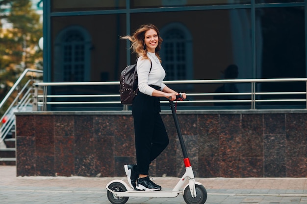 Jeune femme avec scooter électrique dans la ville