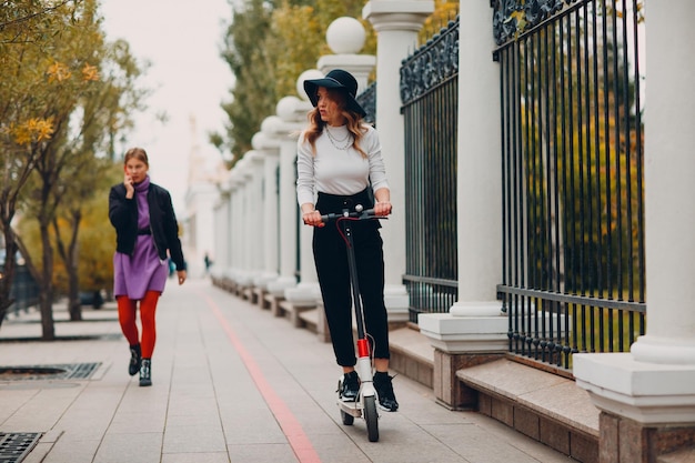 Jeune femme avec scooter électrique dans la ville