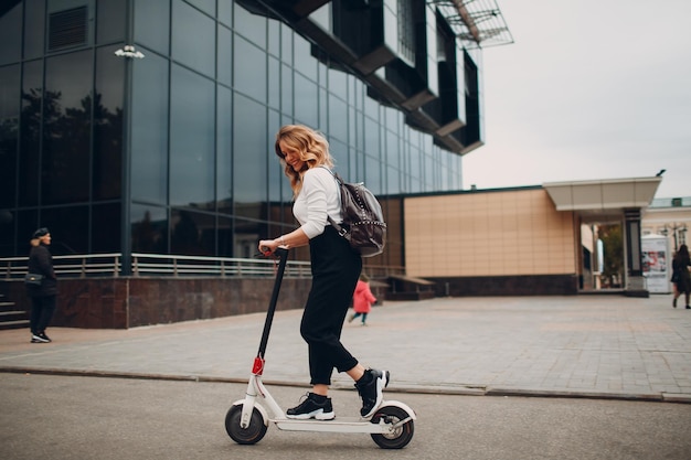 Jeune femme avec scooter électrique dans la ville
