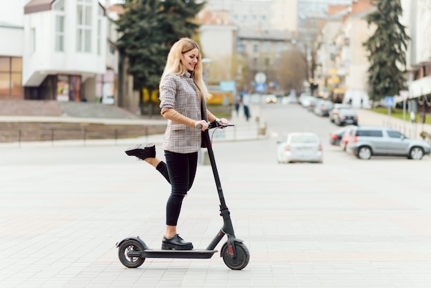 Jeune femme avec scooter électrique dans la ville