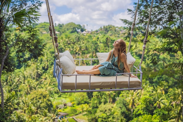 Jeune femme se balançant dans la forêt tropicale de la jungle de l'île de Bali Indonésie Balançoire sous les tropiques Balançoires tendance de Bali