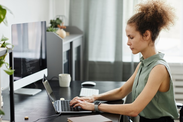 Photo jeune femme se concentrant sur son travail en ligne, elle était assise sur son lieu de travail et tapait sur un ordinateur portable au bureau