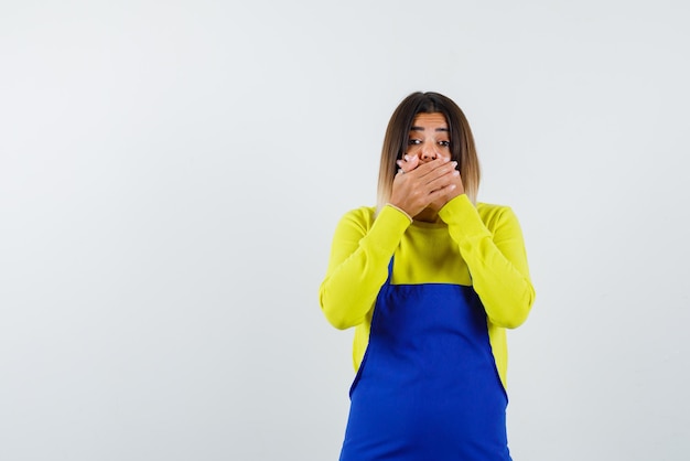 La jeune femme se couvre la bouche avec les mains sur fond blanc