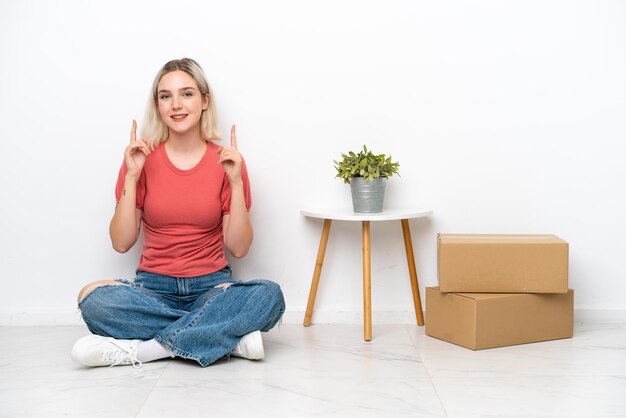 Jeune femme se déplaçant dans une nouvelle maison parmi des boîtes isolées sur fond blanc pointant vers le haut une excellente idée