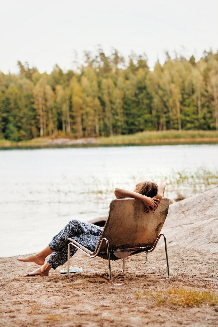 Photo une jeune femme se détend sur une chaise au bord du lac contre le ciel