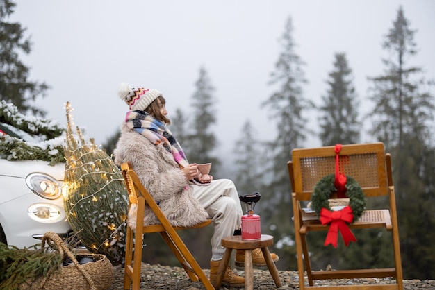 Photo une jeune femme se détend et profite du calme sur la nature pendant les vacances d'hiver a un pique-nique tout en voyageant en voiture dans les montagnes concept de célébrer le nouvel an seule sur la nature