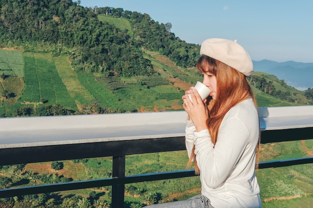 Jeune femme se détendre et boire du café sur Mountain Cafe