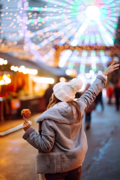 Jeune femme se détendre en buvant du café dans la Foire de Noël Festive Vacances d'hiver Lumières autour