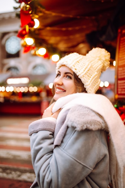 Jeune femme se détendre en buvant du café dans la Foire de Noël Festive Vacances d'hiver Lumières autour