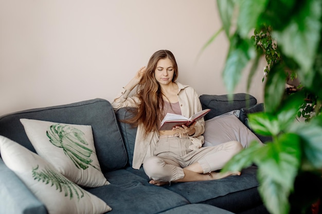 Jeune femme se détendre sur le canapé et lire un livre