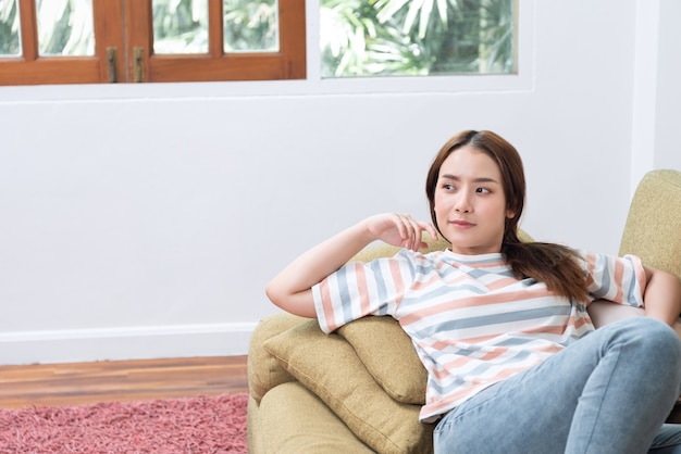 Jeune femme se détendre sur le canapé à la maison