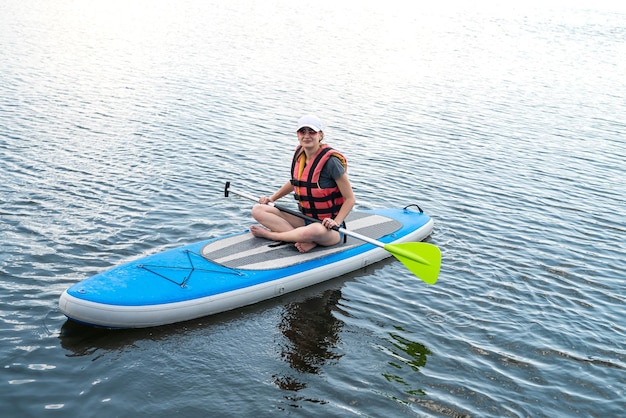 Jeune femme se détendre sur SUP Stand up paddle board en été