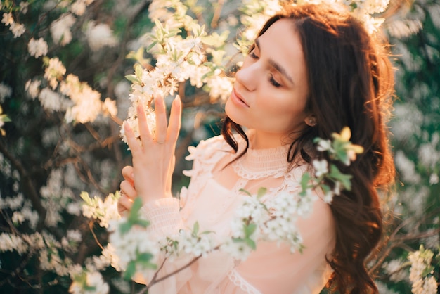 Une jeune femme se dresse contre la surface des arbres en fleurs