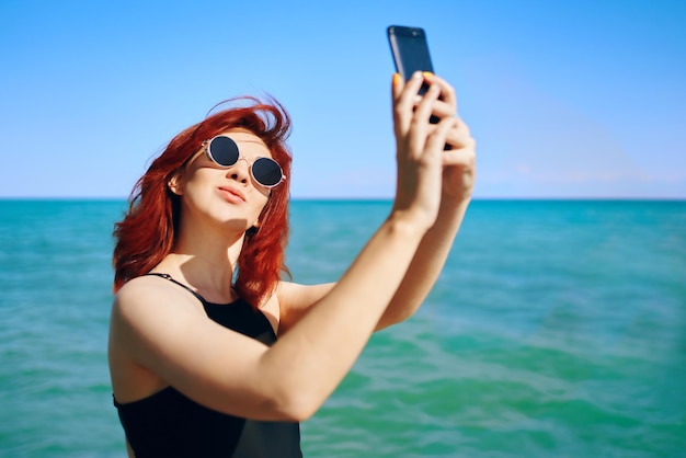 Une jeune femme se fait un selfie en mer contre le ciel.