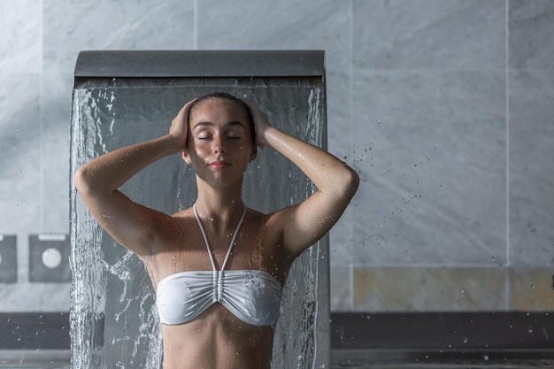 Une jeune femme se lave les cheveux sous la douche dans un spa.