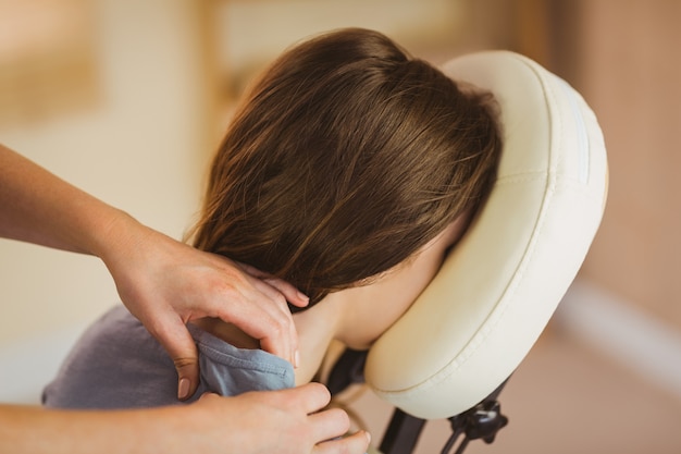 Jeune femme se massage en chaise