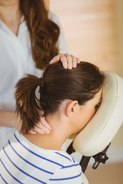 Jeune femme se massage dans une chaise