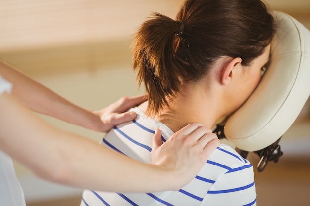 Jeune femme se massage dans une chaise