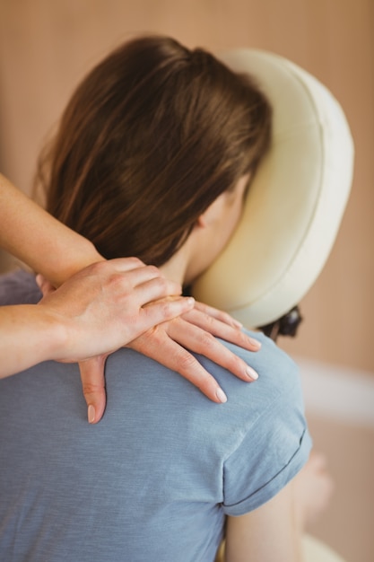 Jeune femme se massage dans une chaise