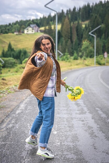 Une jeune femme se promène dans les montagnes avec un bouquet de tournesols