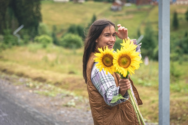 Une jeune femme se promène dans les montagnes avec un bouquet de tournesols