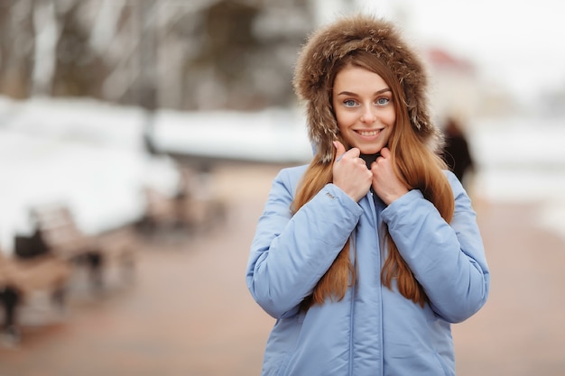 Jeune femme se promène dans le parc d'hiver. Parc d'hiver dans la neige. Concept de photo publicitaire de vêtements.