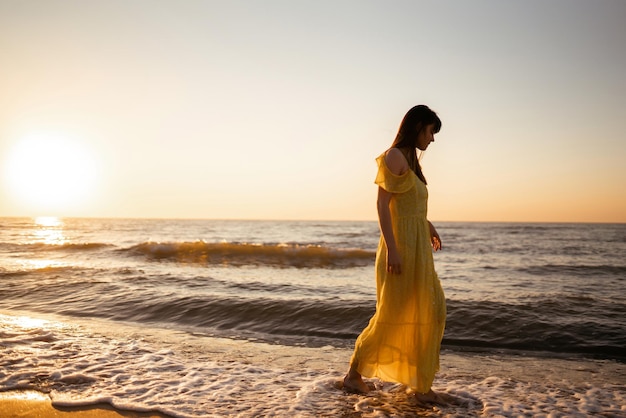 Jeune femme se promène le long du bord de mer au coucher du soleil Nature relax lifestyle concept