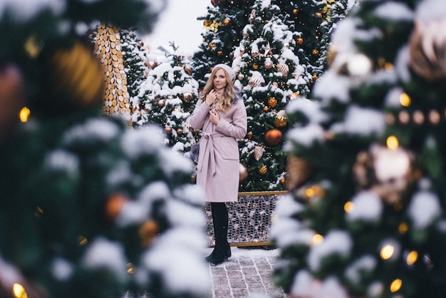 Une jeune femme se promène à Noël sur la place près des arbres de Noël décorés. Candy est une sucette en forme de coeur.