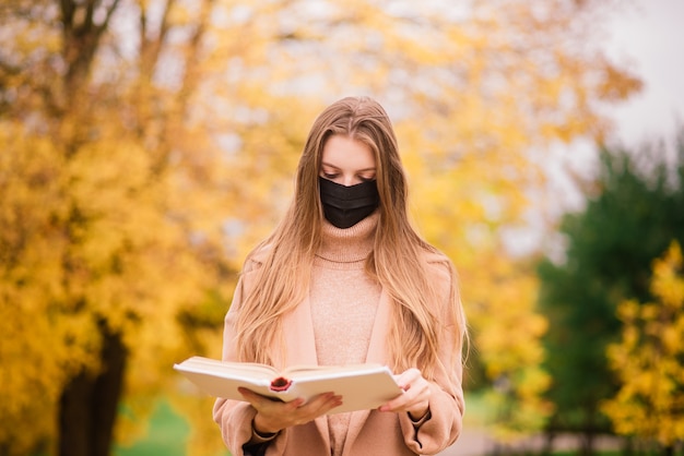 Une jeune femme se protégeant du virus corona en marchant dans un parc. Fond d'automne.